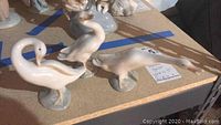 Three Lladro geese figurines arranged on table showing side and front angles, glossy white porcelain with beige accents