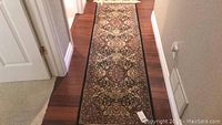 Long view of the oriental style wool runner carpet with intricate floral and medallion patterns in dark colors.