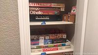 Shelves with multiple stacked board game boxes including Battleship, Stratego, Othello, Pictionary.