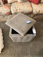 Gray storage ottoman with removable lid showing interior storage space.