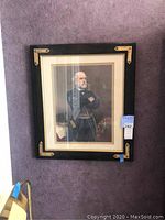 Black framed print of Robert E. Lee with gold decorative corner accents, mounted on purple wall.