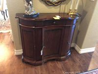 Curved front wood hall cabinet with decorative molding and small metal drawer knob