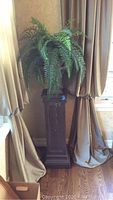 Full height side view of pedestal with urn and artificial Boston fern