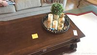 Top view of the wooden coffee table showing decorative tray with plant, candles, and gold pineapple figurine.