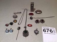 Group shot of compacts, jewelry items including earrings, rings, necklaces, brooches, hatpin, pendant