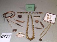 Full lot overview displaying collection of vintage jewelry, brooches, necklaces, and antique pens