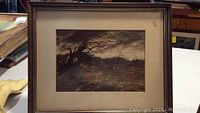 Frontal photo of one framed painting showing the bent tree, hill, sky and mat discoloration. Painting is signed in lower right.