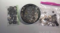 Overview of the lot showing multiple older American nickels in a black plastic container and two clear ziplock bags.