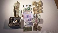 Overview of box with assorted coins and scattered banknotes of various countries