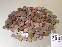 Large pile of assorted foreign coins including British, Canadian, French, and Spanish in various metals and sizes.