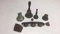 Full overview of all 8 bells showing their variety in shape, size, and materials.