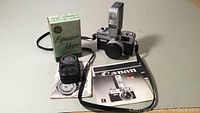 Photo showing the Canonet camera with Canolite D flash mounted, GE exposure meter in box, and user manuals