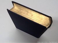 Top-edge view of one hardcover book with gold-edged pages.