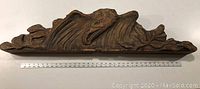Front view of the hand carved wooden eagle showing detailed eagle head and feathers with a ruler for scale.