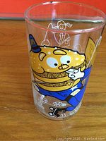 Front side of the glass showing the hamburger character dressed as a policeman with a blue uniform and hat