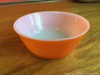 Front angle showing the bright orange exterior and white interior of the small shallow bowl.