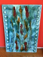 Front view of ceramic wall hanging showing full rectangular piece with turquoise glaze and red, brown decorative elements, with raised round bead detailing along short sides.