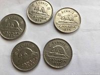 Front side of five Canadian nickels showing the beaver design and dates 1937, 1938, 1939, 1930, 1934.