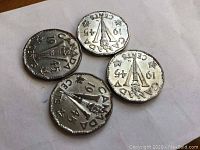 Set of four Canadian Victory nickels 1945 showing torch and large V design with denomination and maple leaves, coins on white paper background.
