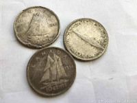 Three old Canadian 10-cent coins, two dated 1914 and one with an obscured date, all showing the Bluenose schooner design on the reverse.