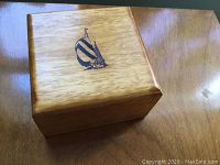 Closed view of the Nautica wooden box showing the polished hardwood finish and Nautica sailboat logo on the lid.