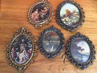 Five vintage Italian oval frames with intricate brass designs each containing classical art prints showing romantic and pastoral scenes.