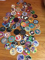 Full layout of all 63 pogs on a wooden surface showcasing various designs and colors