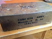 Photo of the full brown box with black stenciled text 'CANADIAN ARMY Monopack Ration (ARCTIC)' on the side.