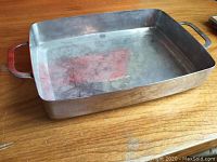 Top and angled view of rectangular stainless steel baking dish on wooden surface.