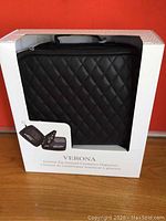 Front view of black quilted cosmetics organizer in white packaging with cutout showing the item inside.