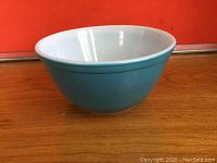 Front view of vintage turquoise Pyrex mixing bowl showing glossy turquoise exterior and white interior.