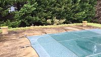 Wet pool cover and concrete patio with solar lights visible around the pool perimeter.