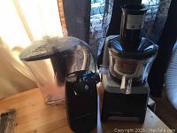 Georges Laroque juicer, Brita water filter jug, and Proctor Silex electric can opener arranged on wooden surface with curtains in background