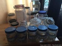 Full set of various glass jars and storage containers including decorative goose jars, pasta jars, and plastic containers on a wooden surface.