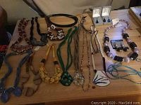 Top down view of assorted handmade necklaces and earrings on wooden surface