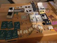 Full assortment of earrings laid out on a table showing mixed styles and materials.