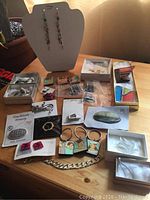 Full collection of pins, keychains, bracelet, and earrings displayed on table with some items in boxes and on a stand.