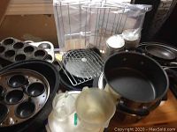 Photo of assorted kitchen items including non-stick pots, muffin pan, measuring cups, and other bakeware items.