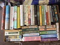 Books arranged standing and stacked, showing spines and covers of titles by Hilderbrand, Kinsella, Moses, Flagg, Binchy, Steel, and others.
