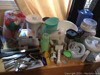 Full view of the collection showing juicers, mixers, jugs, and kitchen tools on wooden table against curtain background