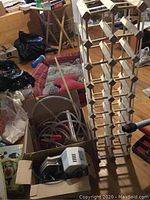Photo showing the wooden wine rack, wine tubing, and the Burn Vino pump device inside an open box indoors