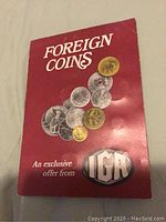 Front cover of red booklet titled 'Foreign Coins' showing images of coins and IGA logo.