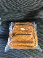 Front view of mustard yellow quilted crossbody purse sealed in original plastic, showing front zipper pockets and tag.