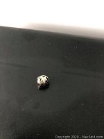 Close-up photo of Pandora charm with gold stars on black background showing front side