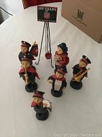 Overview of six figurines and sign stand on white tablecloth