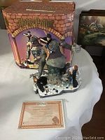 Photo showing the figurine with original box in background and certificate of authenticity in front.