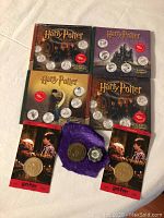 Four sealed Harry Potter collectible coin set boxes and four collectible coins shown in original packaging and display pouches.