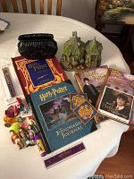 Photo showing a table with the fibre optic Hagrid's home figurine, Harry Potter books and journals, several miniature figurines, and small items laid out.