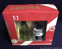 Boxed set of Cucina Coriander & Olive Tree hand soap, hand cream, and bamboo cutting board in original packaging with red and white design.