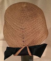 Top view showing the finely woven straw material and black bow tied at the back